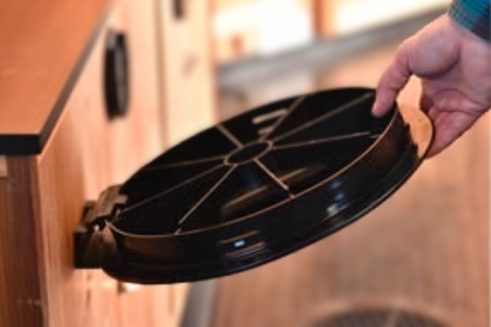 A person is holding a Catch Cover Handle Trap (Handle Cover) - CC11 in a kitchen cabinet.