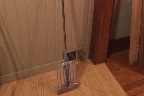 A Amish Stainless Steel Fishing Spear 7-tine on a wooden floor.