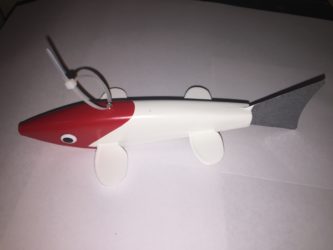 A red and white toy fish on a white surface.