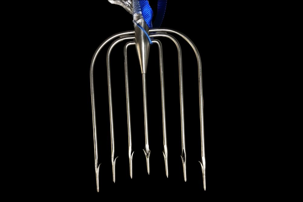 An Amish Stainless Steel Fishing Spear 7-tine with a blue ribbon on it.