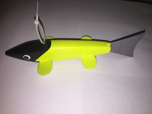 A yellow and black toy fish on a white surface.