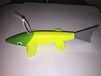 A yellow and gray wooden fish toy on a white surface.