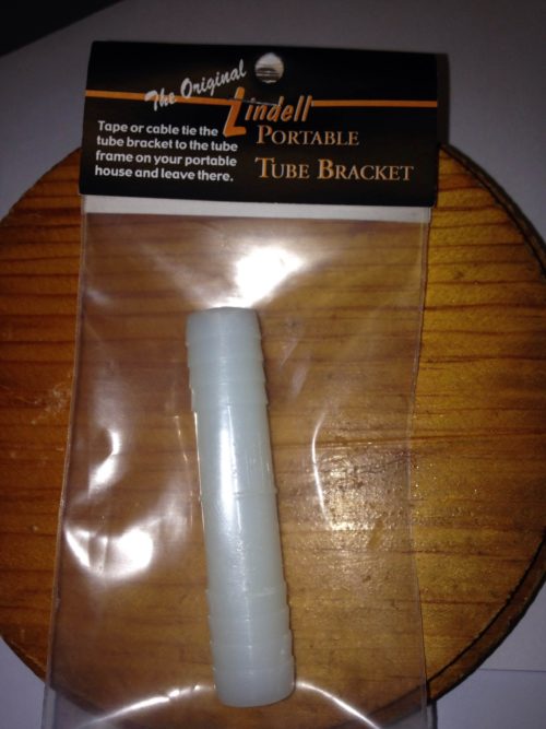 A Lindell Ice Rig Tube Bracket is sitting on top of a wooden table.