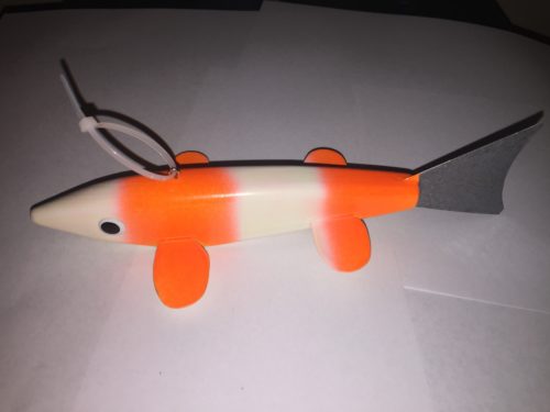 An orange and white toy fish on a white surface.