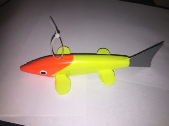 A yellow and orange toy fish on a white surface.
