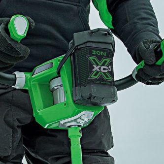 A person in a green jacket is holding a 24510 Kit ION Battery XC5 snow shovel.