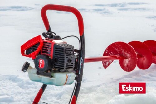 A red Eskimo Stingray 33cc 2-Cycle Viper® Engine Ice Auger is sitting on top of a pile of snow.