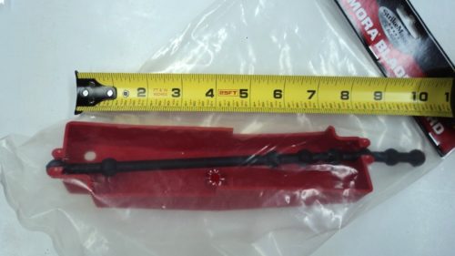 A red plastic Strikemaster Mora Auger Blade Guard 7 8 BG-7-8 with a ruler next to it.