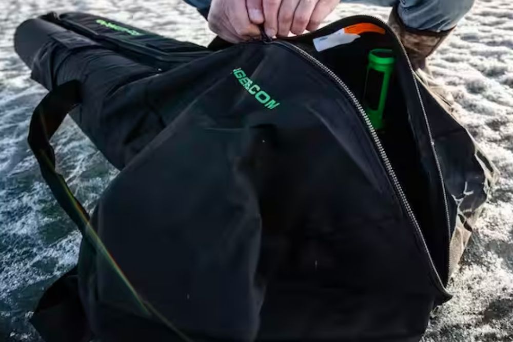 A person is holding an ION Auger Bag 24245 on the ice.