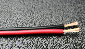 Two 16 GAUGE 100 FT RED BLACK WIRES on a black surface.