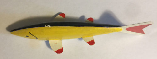 A yellow and black 6-1/2 Inch Lamont Mounsdon Wood Spearing Decoys on a white surface.