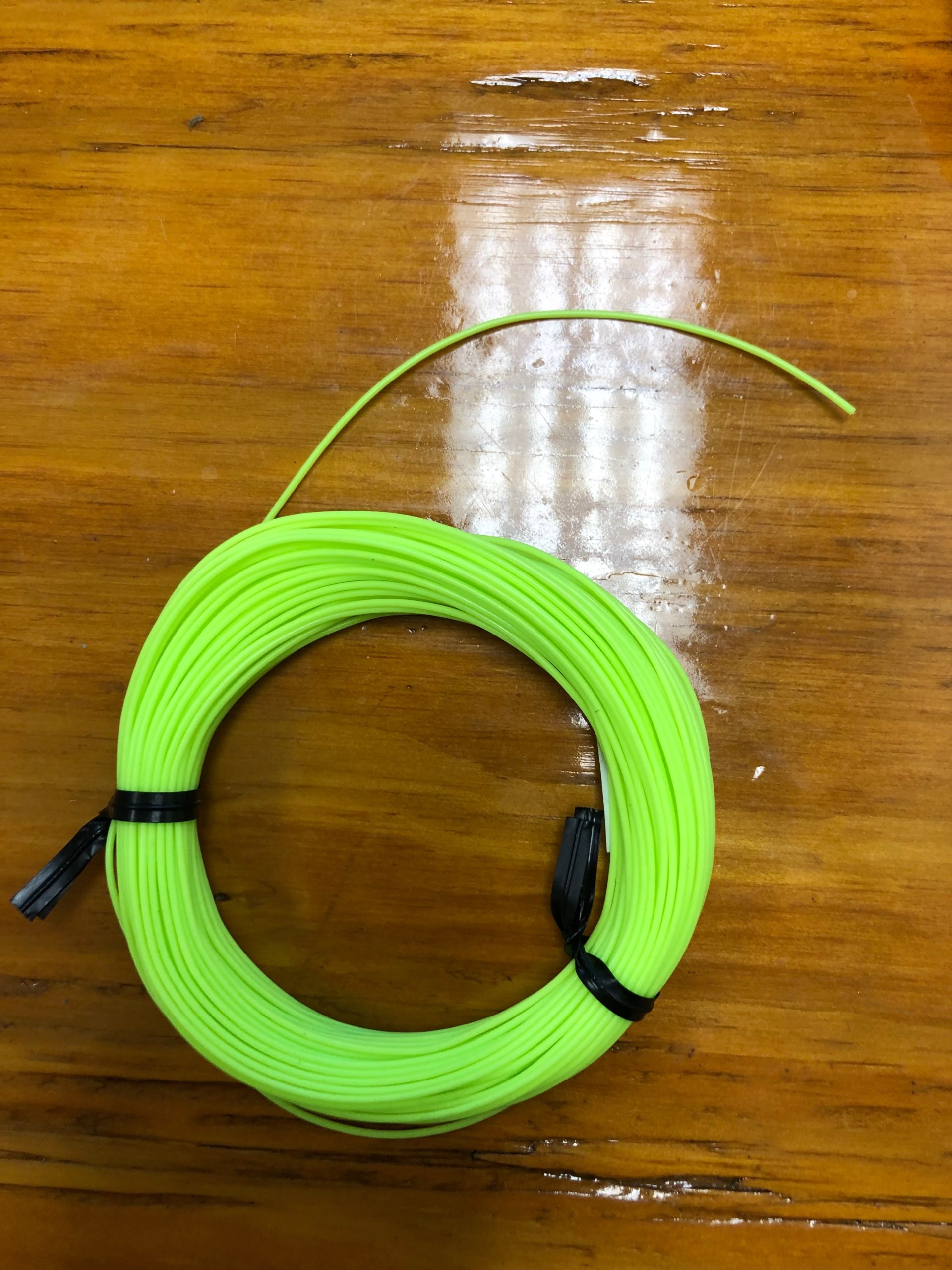 A green fishing line on a wooden table.
