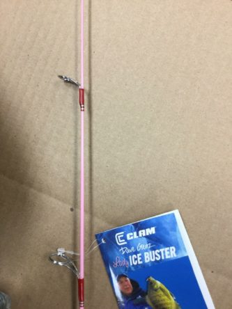 A Clam Lady Ice Buster Ice Fishing Combo 24" 9574 with a book on it.