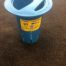 An Ice Well Live Well for ice fishing/ summer fishing with a lid sitting on the floor.
