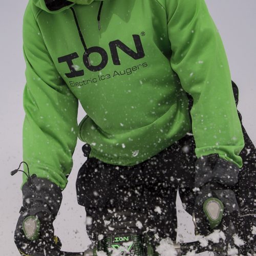 A man in an Ion Performance Hoodie riding a snowmobile in the snow.