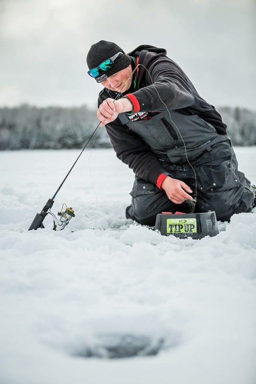 A man is holding a I Fish Pro 2.0 Tip Up ifish pro in the snow.