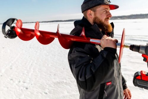 A man is holding an ESKIMO ICE FISHING GEAR PISTOL BIT 8'' or 6" in the snow.