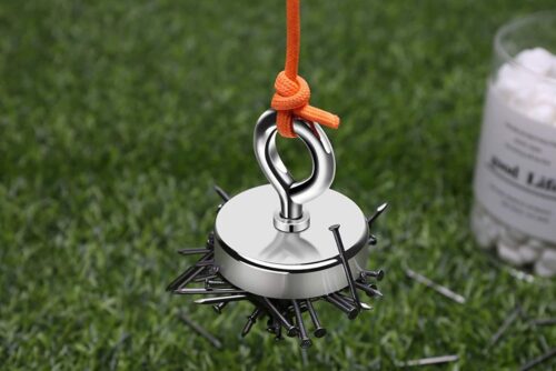 A Fishing Magnet, 300 lb Pull Strength hanging from a string on the grass.