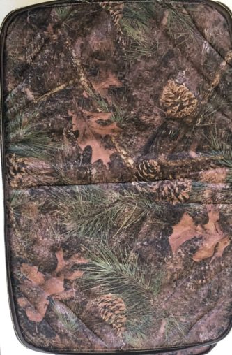 A camouflage seat cover with pine cones and pine needles.