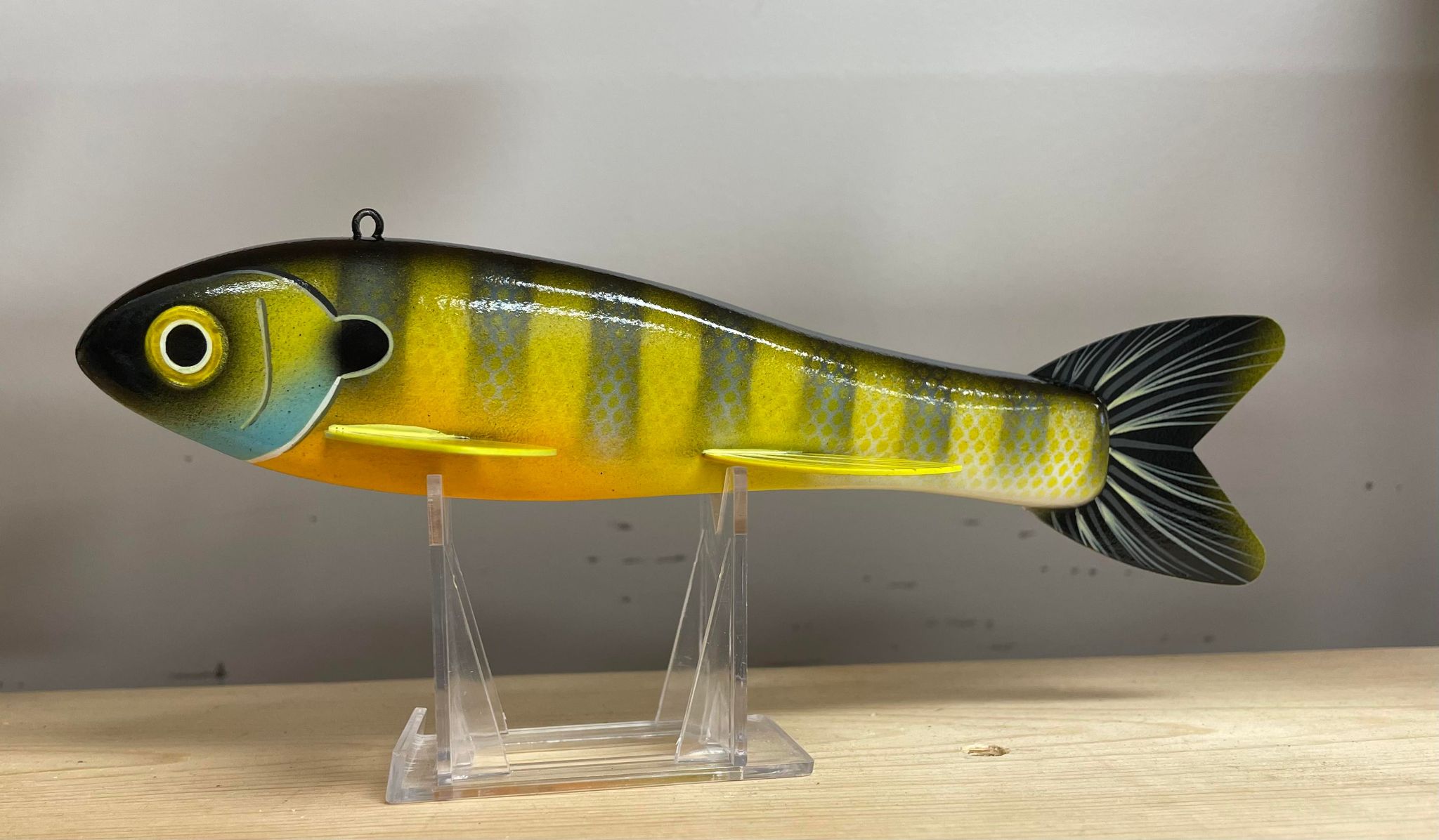A yellow and blue plastic Goodin 9" frog decoy, orange on a stand.