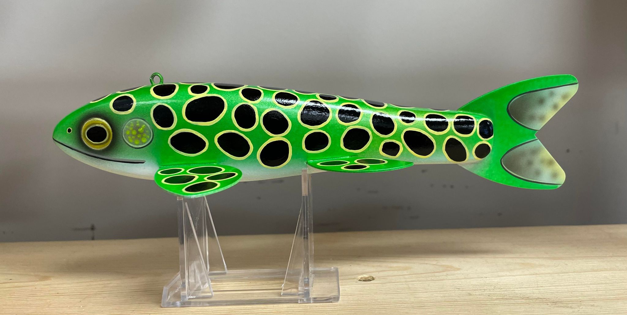 A green and black Goodin 9" frog decoy, orange on a clear stand.
