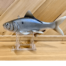 A gray plastic Gizzard Shad sitting on a wooden stand.