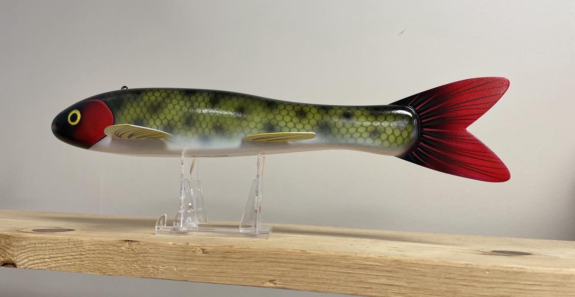A 12" Goodin Red Head Sucker Decoy on top of a wooden stand.